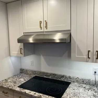 Finished kitchen range-hood installation with white cabinetry